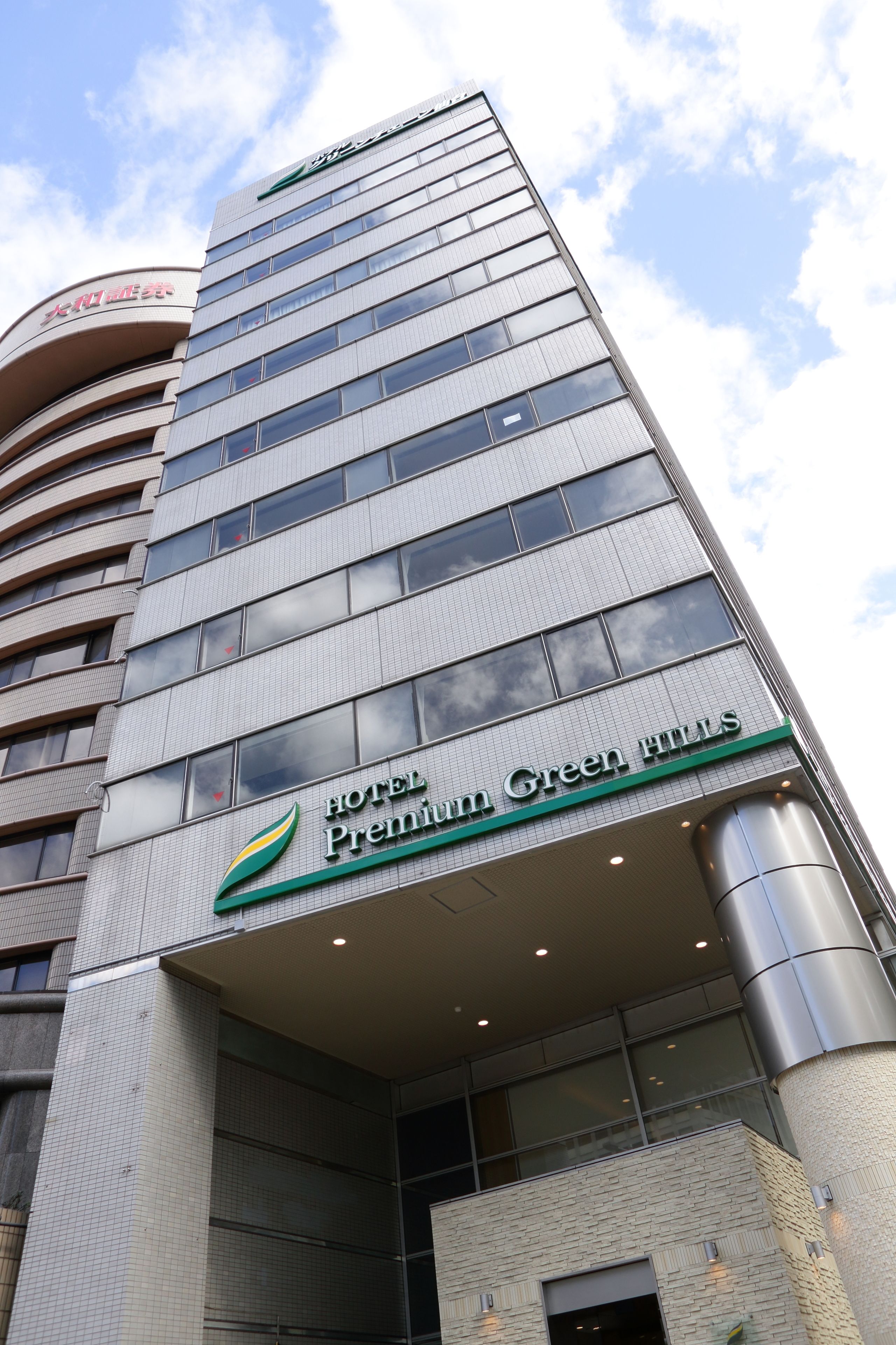 Un moderno edificio de hotel con un letrero llamativo que dice "Hotel Premium Green Hills".