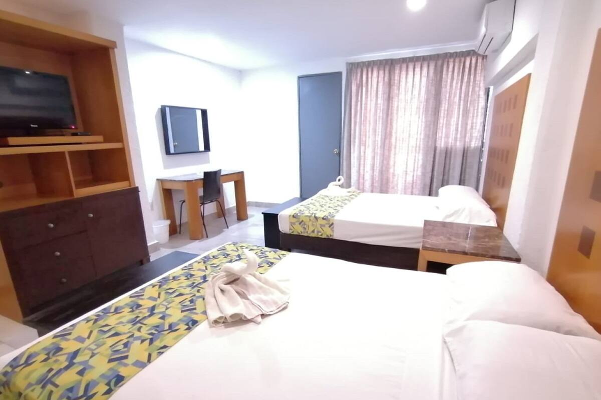 A hotel room with two beds, a desk, a TV, and a wardrobe.