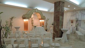 A formal event space with white chairs arranged in rows, a central archway, and floral decorations. - Hotel Ziami (Veracruz)