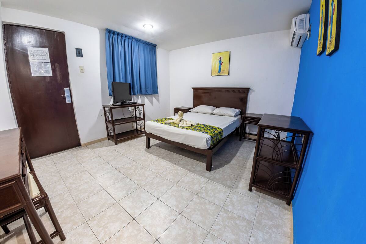 A hotel room with a bed, a TV, a desk, and a chair.