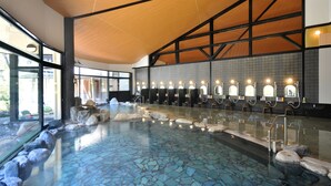 A large indoor swimming pool with a tiled floor, benches, and a wooden ceiling. - Kurobe Kanko Hotel (Omachi)