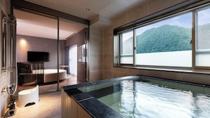 A modern bathroom with a glass-enclosed shower, a bathtub, and a large window offering a mountain view.
