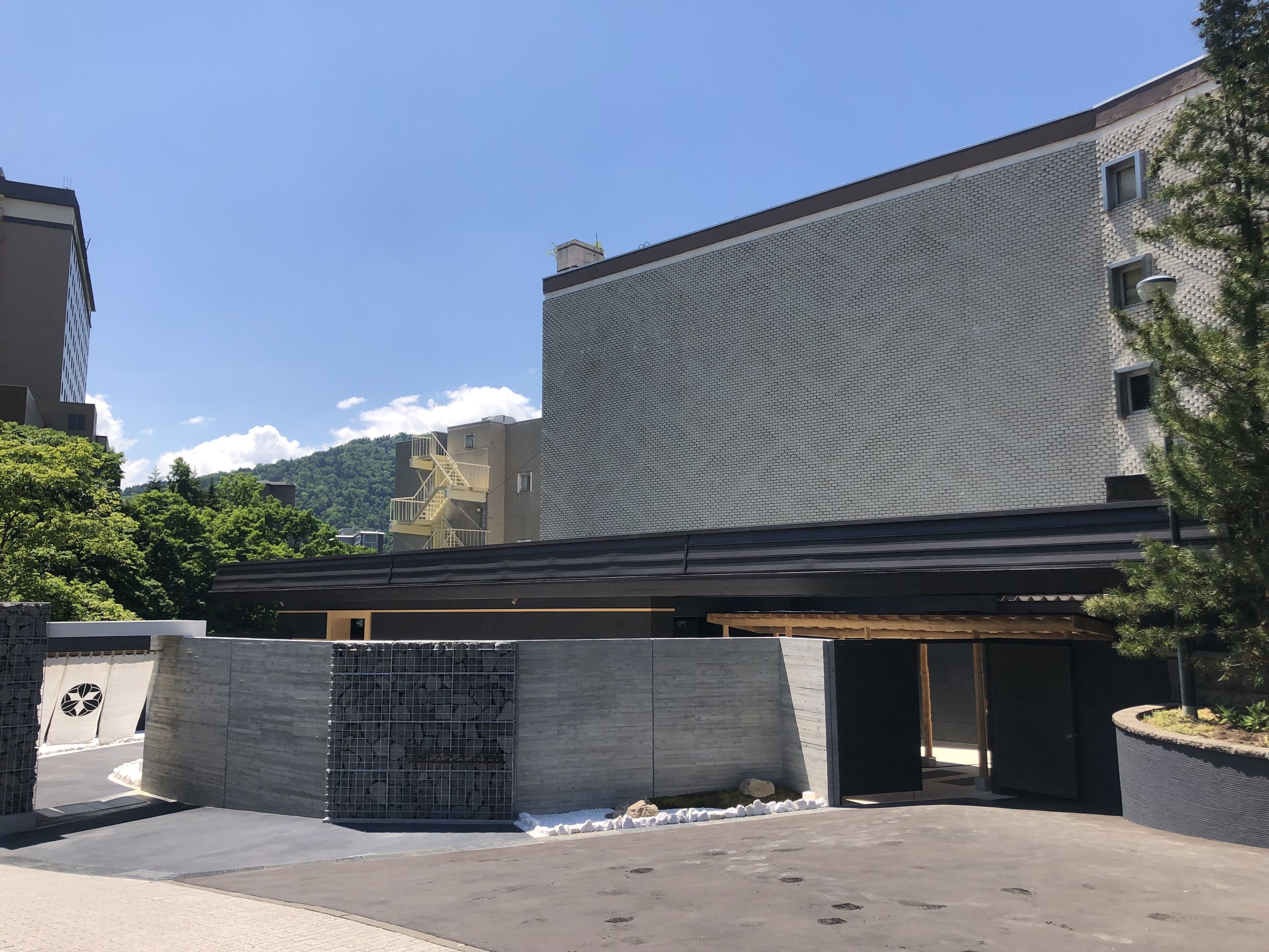 Un edificio moderno con tejado plano, amplia fachada de vidrio y una entrada pequeña.