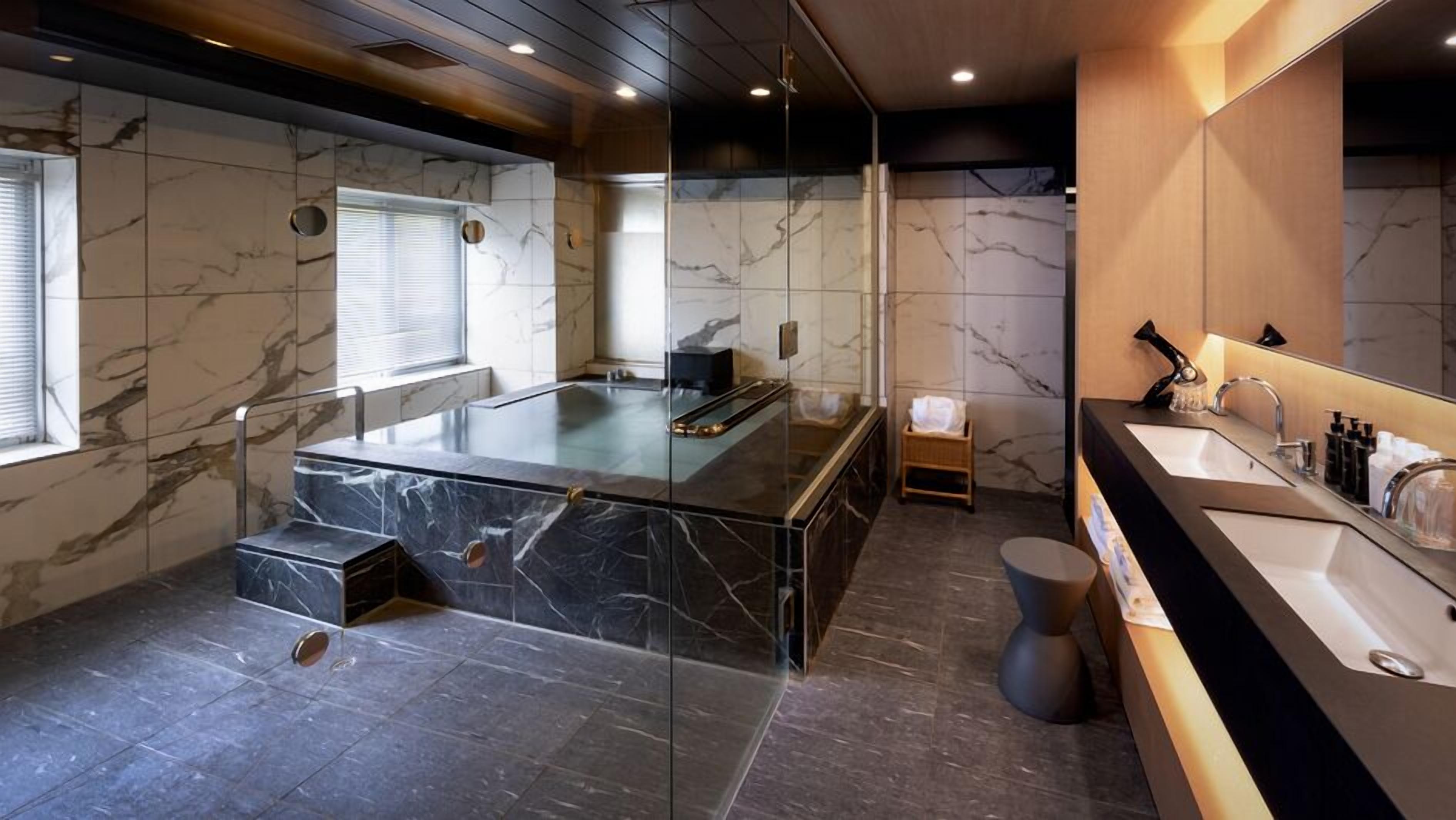A modern bathroom with a glass-enclosed jacuzzi, a separate shower area, and a vanity with a large mirror.