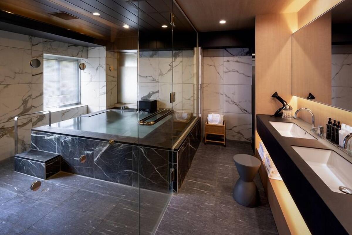 A modern bathroom with a glass-enclosed jacuzzi, a separate shower area, and a vanity with a large mirror.