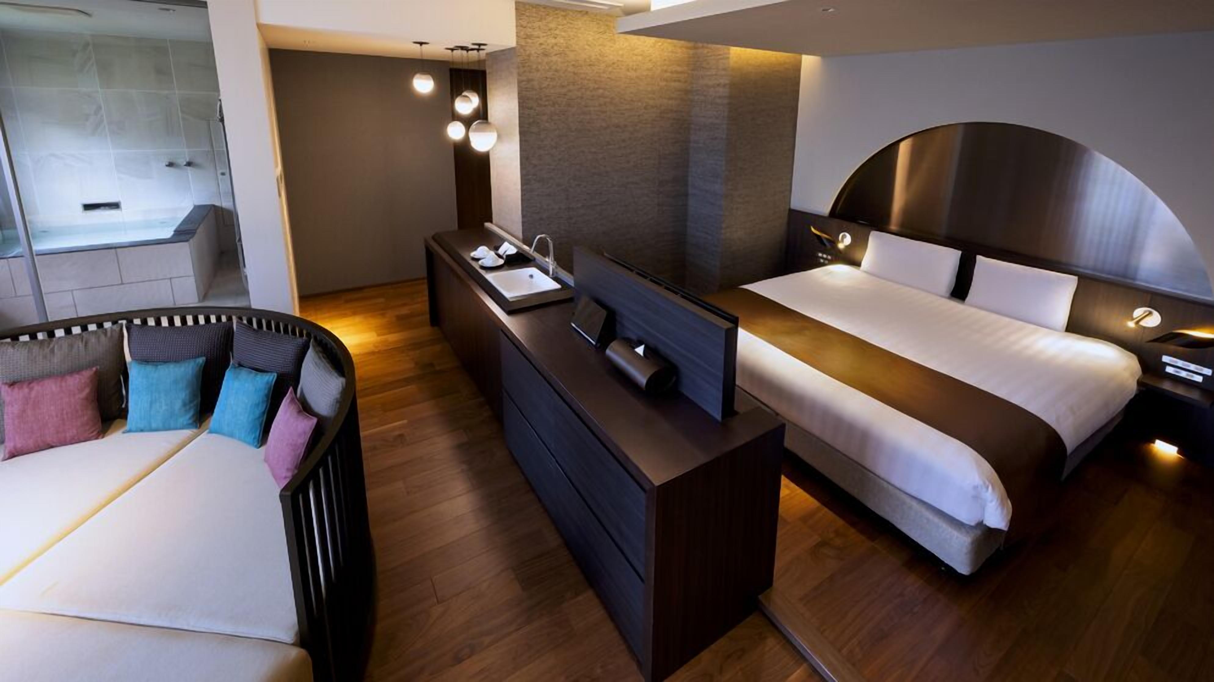 A modern hotel room with a bed, bedside table, and a small desk area.