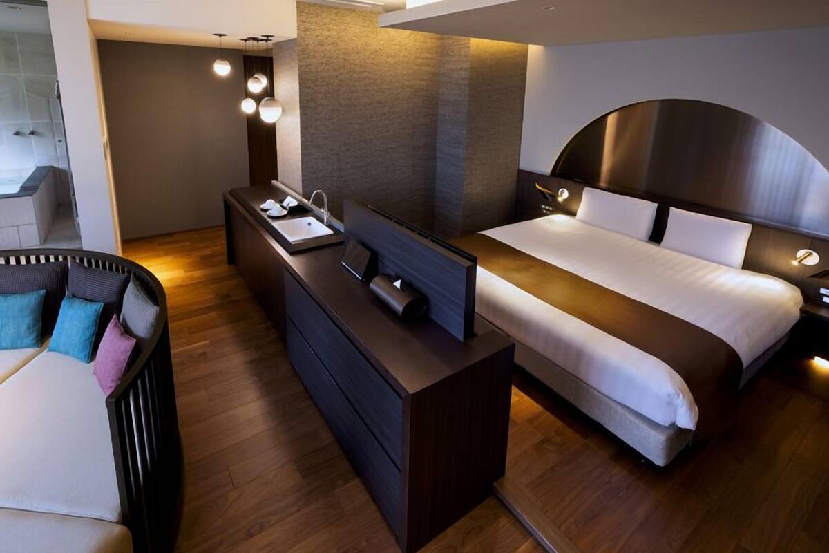 A modern hotel room with a bed, bedside table, and a small desk area.