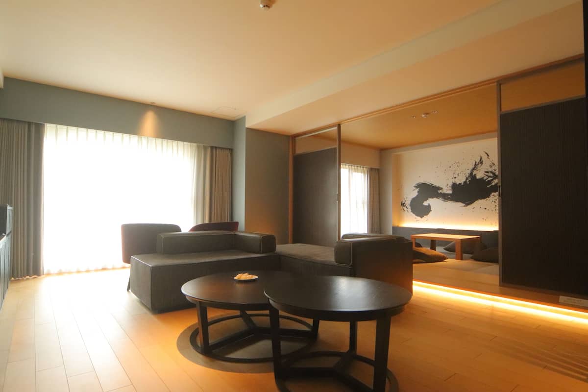 A modern living room with a sectional sofa, two round tables, and a large mirror.