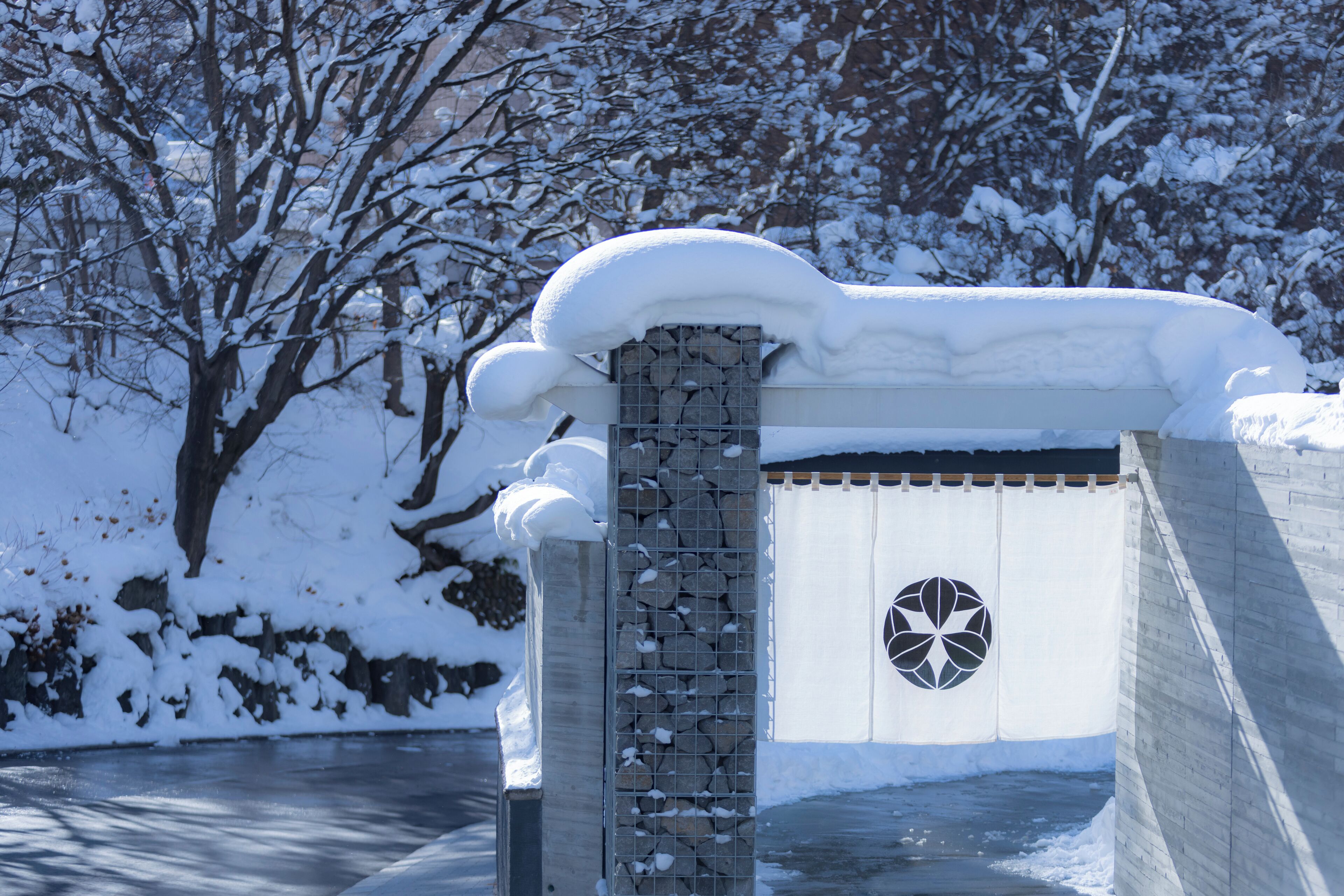 A stone wall with a snow-covered gate and a circular emblem.