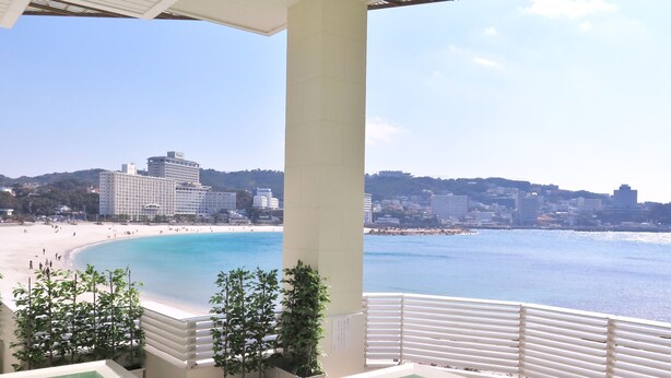 A pool area with a view of a beach and cityscape. - Shiraraso Grand Hotel (Shirahama)