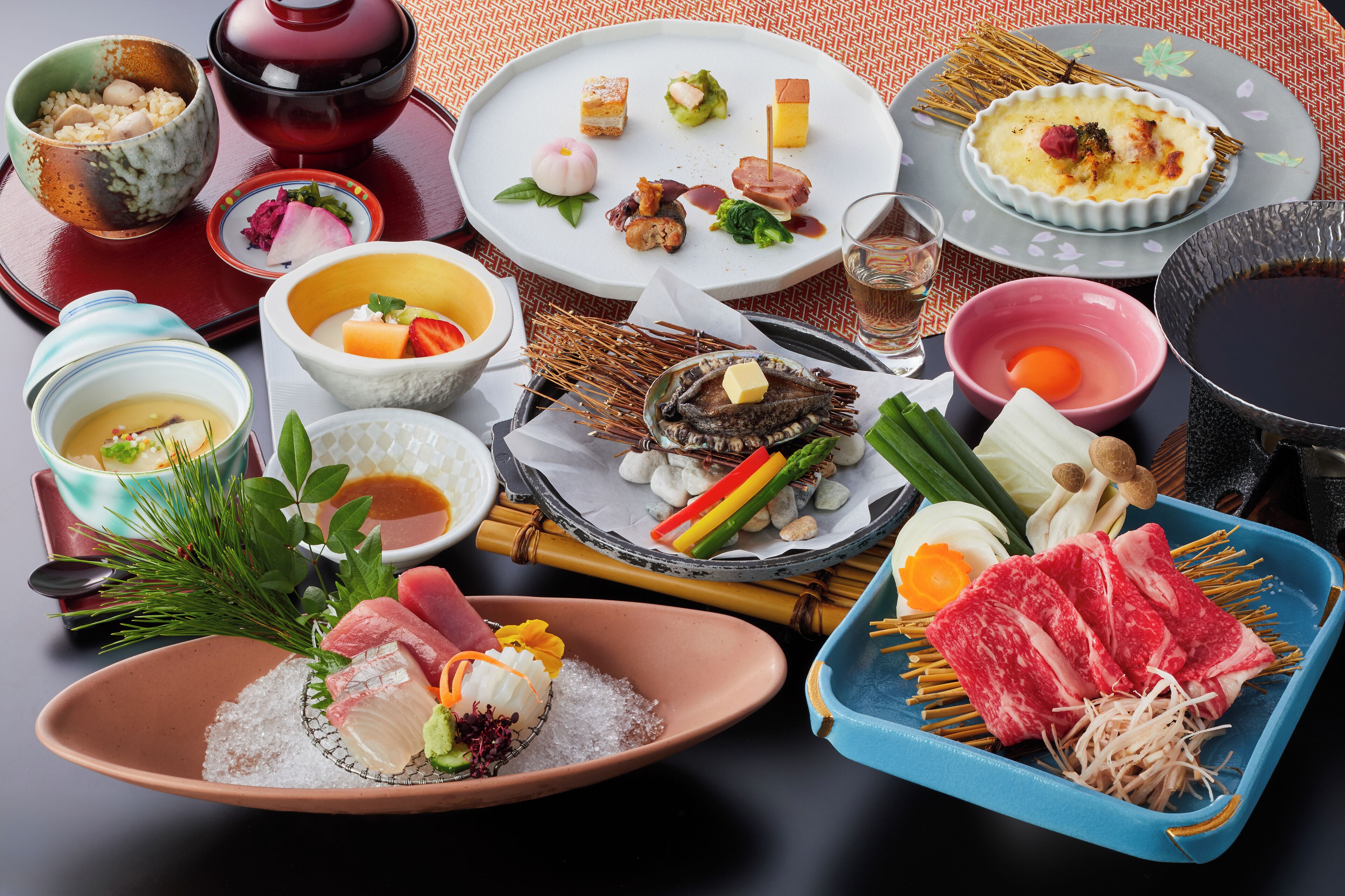 A variety of Japanese dishes including sushi, sashimi, and tempura, arranged on a table with traditional tea sets and bowls.