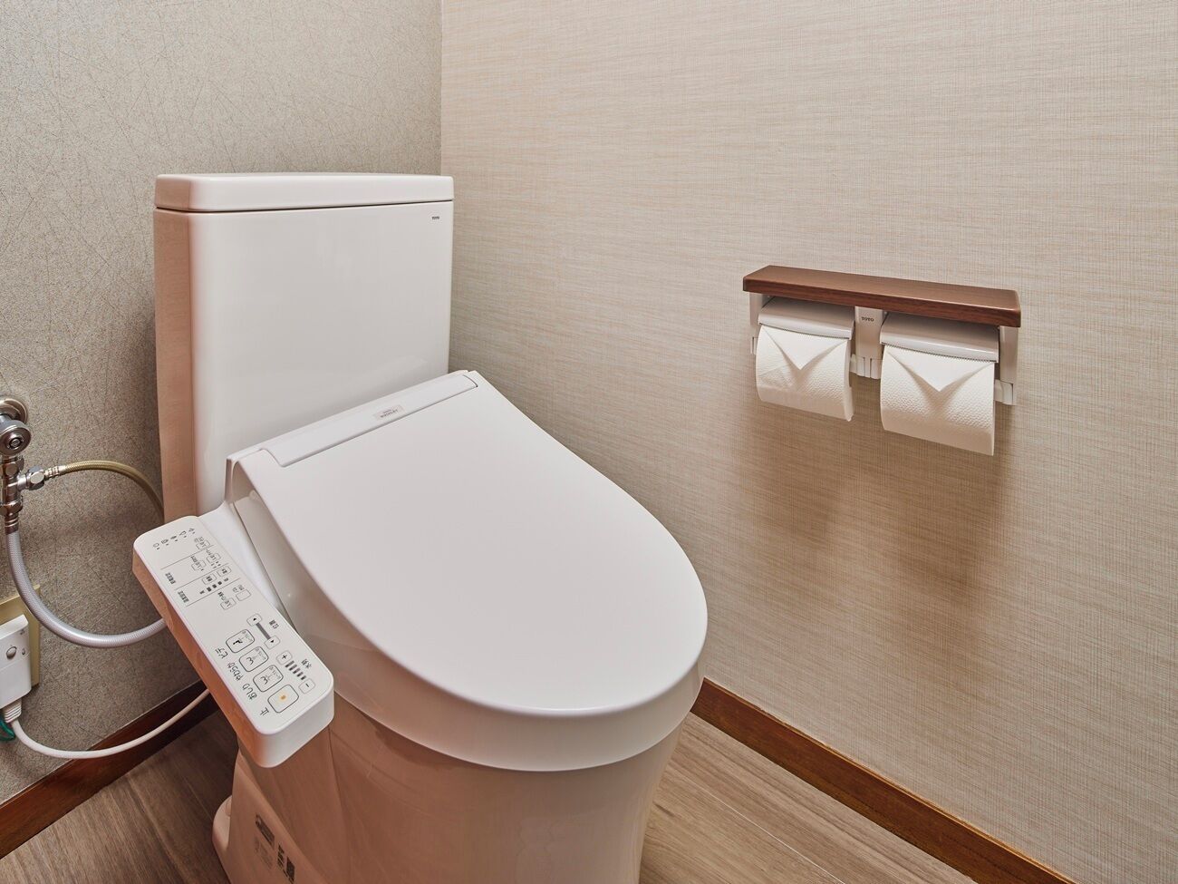 A modern bathroom with a toilet, a control panel, and a towel rack.