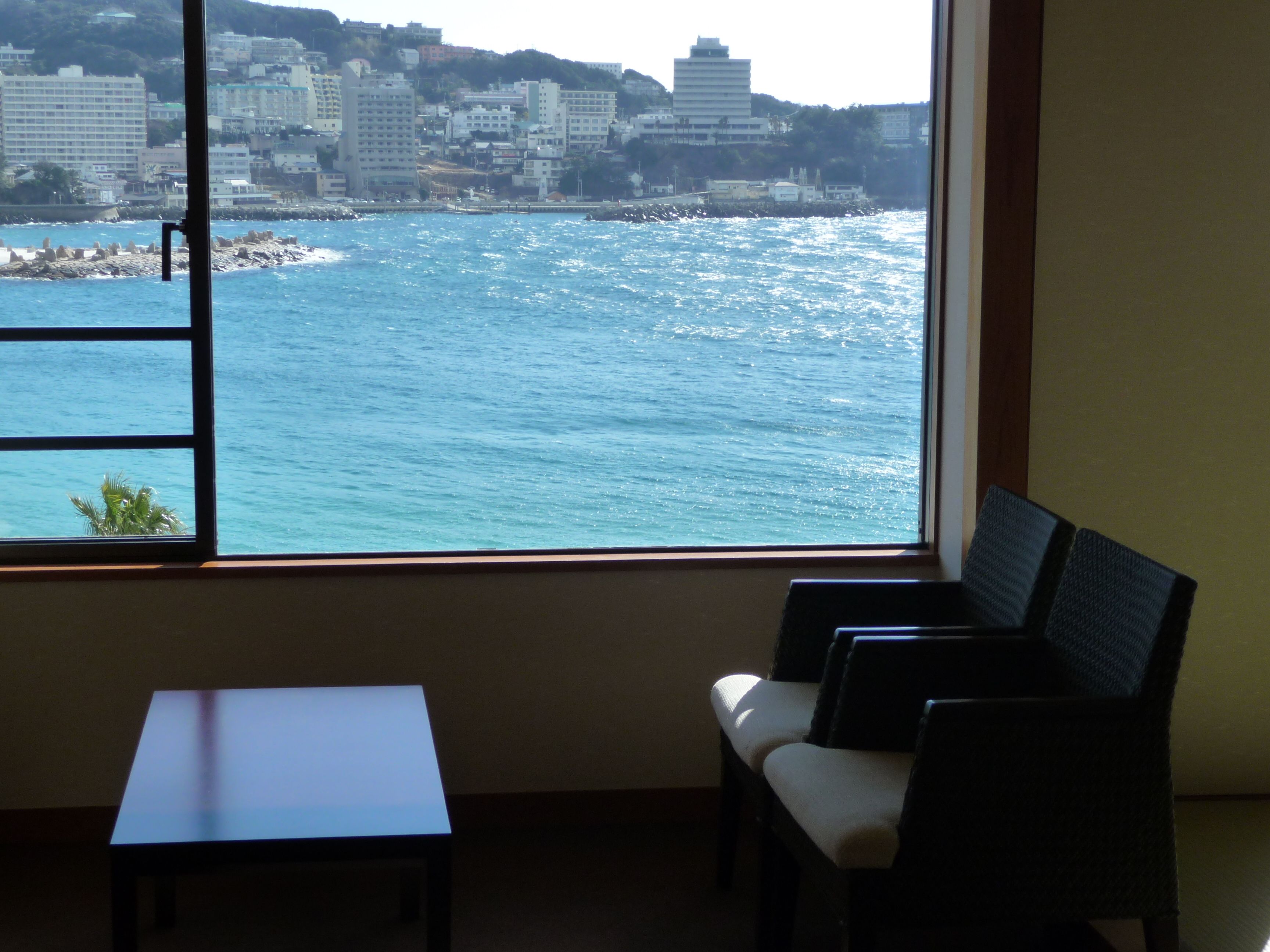 A room with a window overlooking a coastal cityscape.
