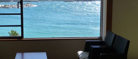 A room with a window overlooking a coastal cityscape.