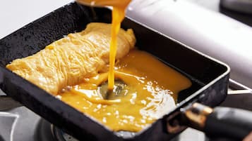 A pan with a golden-brown omelette and melted cheese being poured over it.