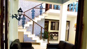 A living room with two sofas, a coffee table with books, and a staircase with blue patterned tiles. - Pousada Estrela do Mar (Salvador)