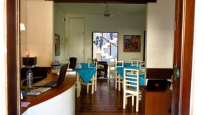A hallway leading to a dining area with a table and chairs, a laptop on a counter, and a ceiling light. - Pousada Estrela do Mar (Salvador)