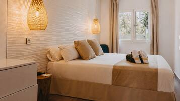 A neatly made bed with pillows, a bedside table, and a hanging light fixture.