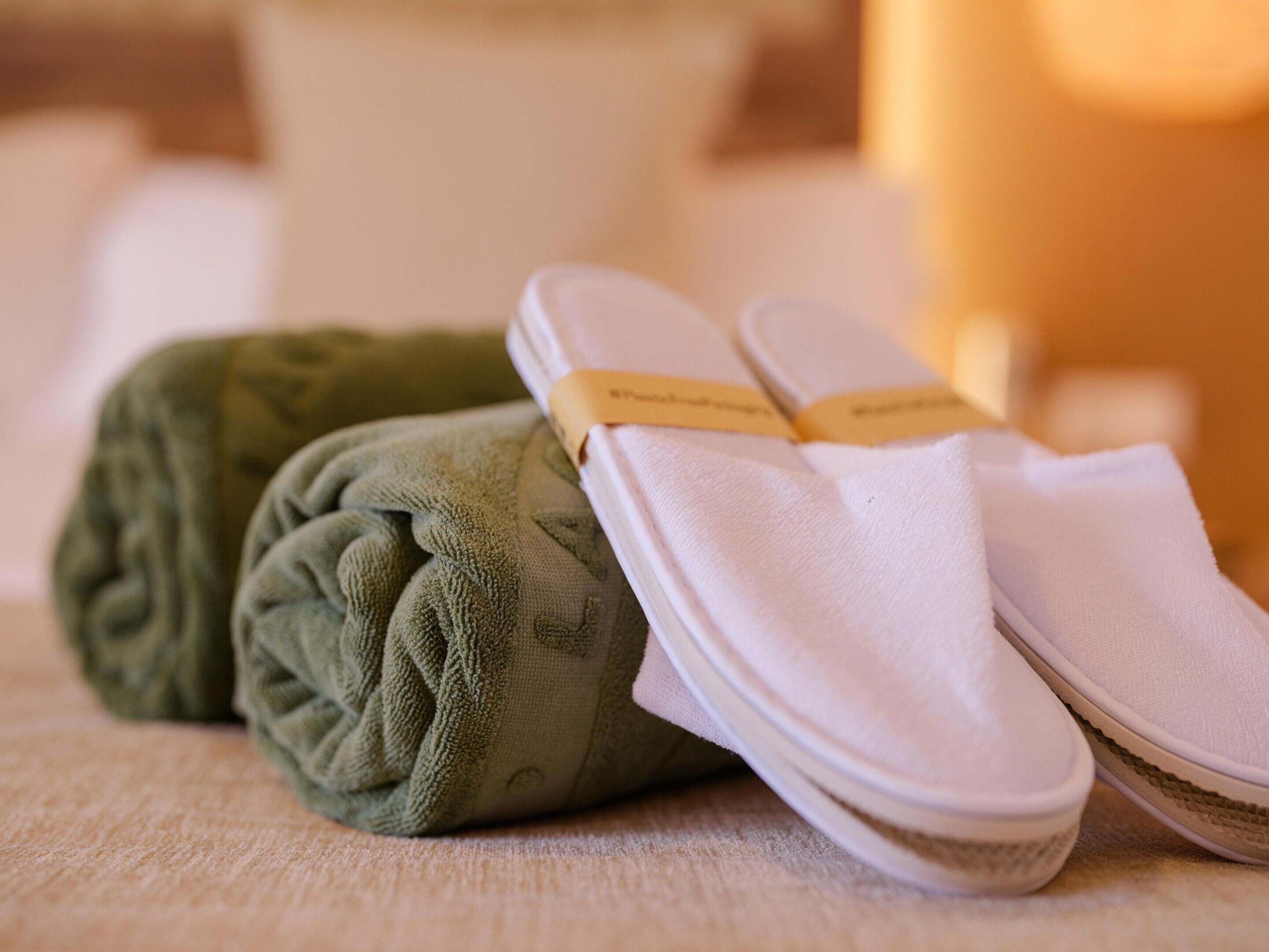 A pair of slippers and a rolled towel on a textured surface.