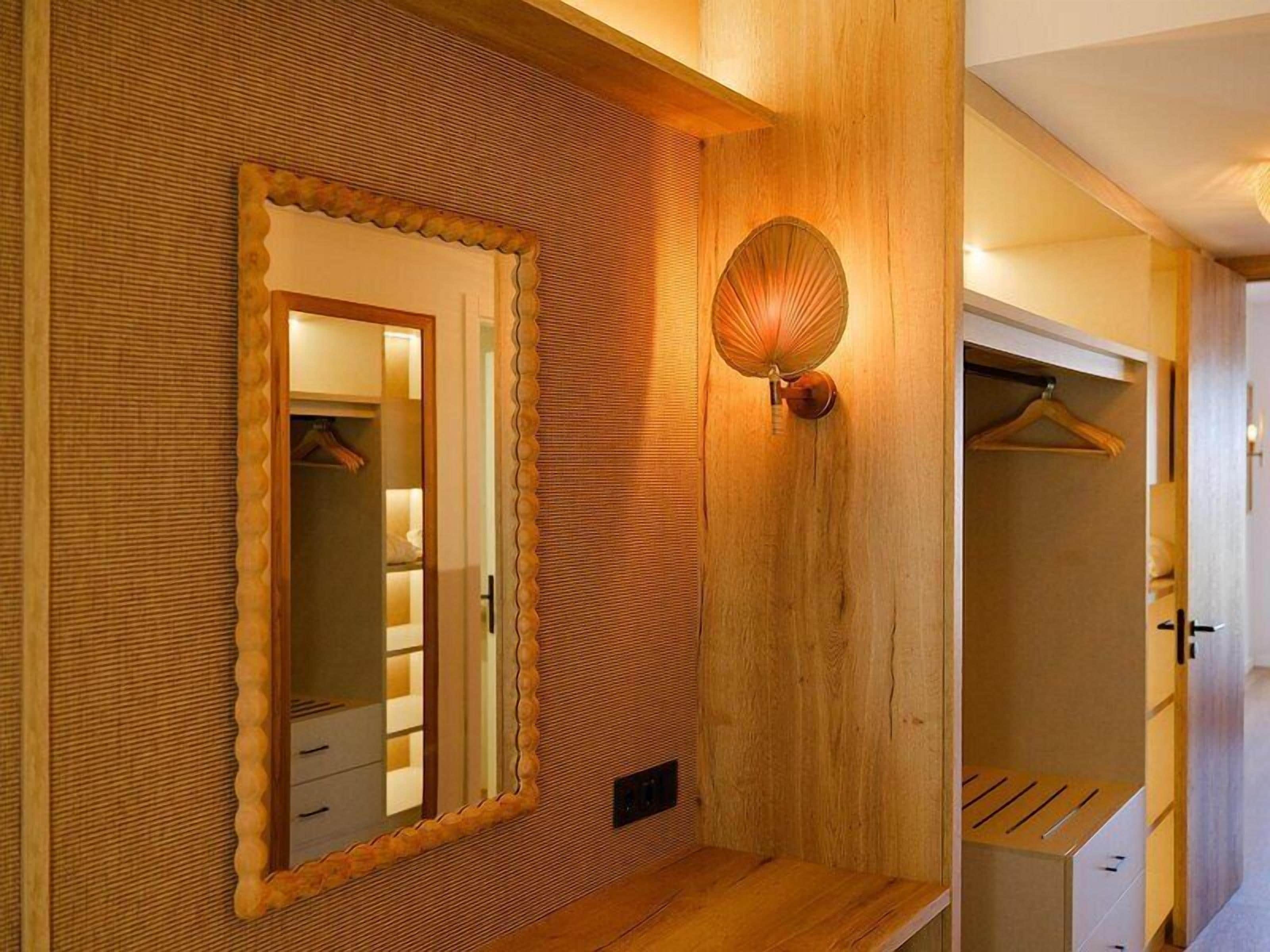 Una pared de madera con un espejo, una lámpara de pared y un banco de madera.
