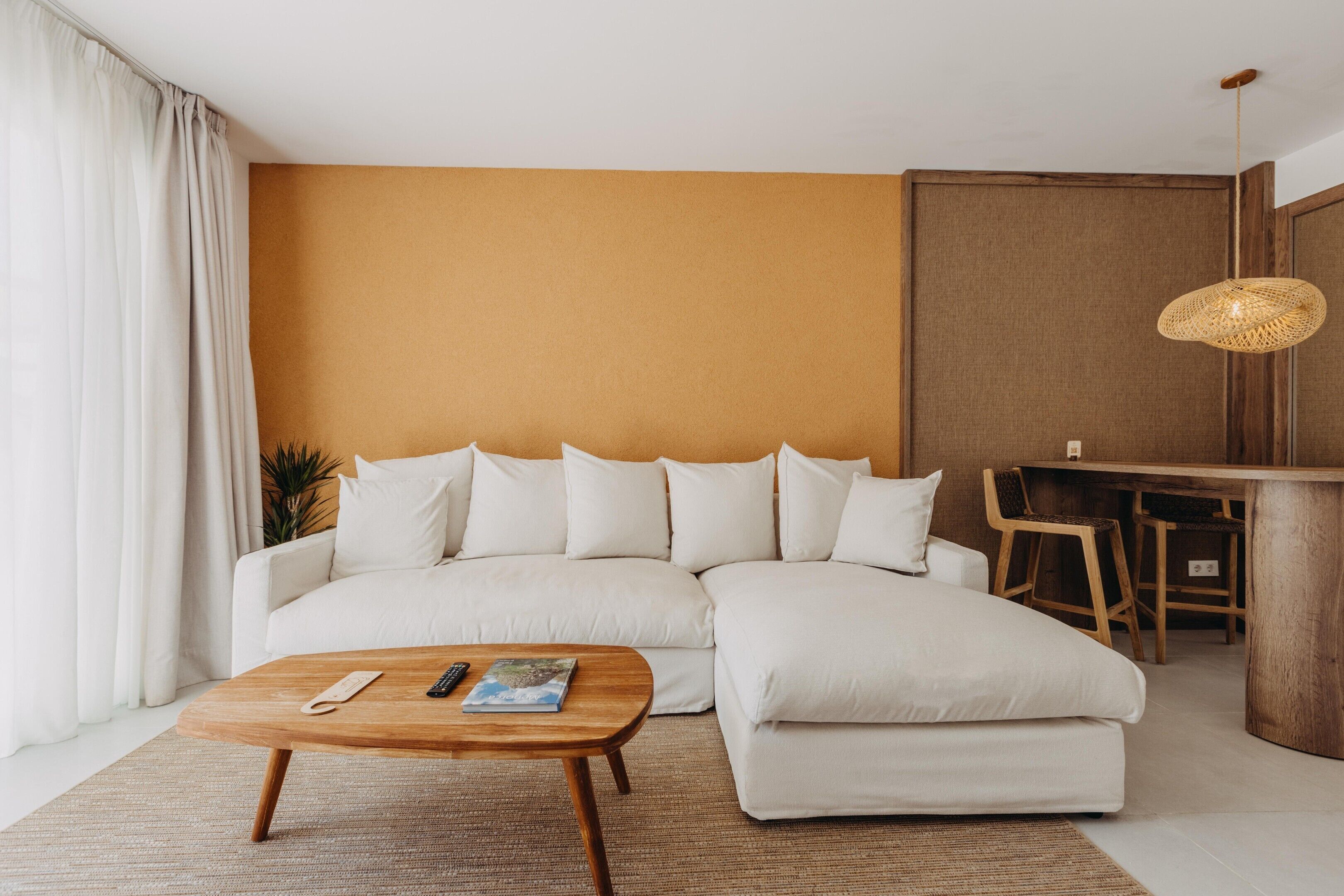 A modern living room with a sectional sofa, a wooden coffee table, and a dining area with a wooden table and chairs.