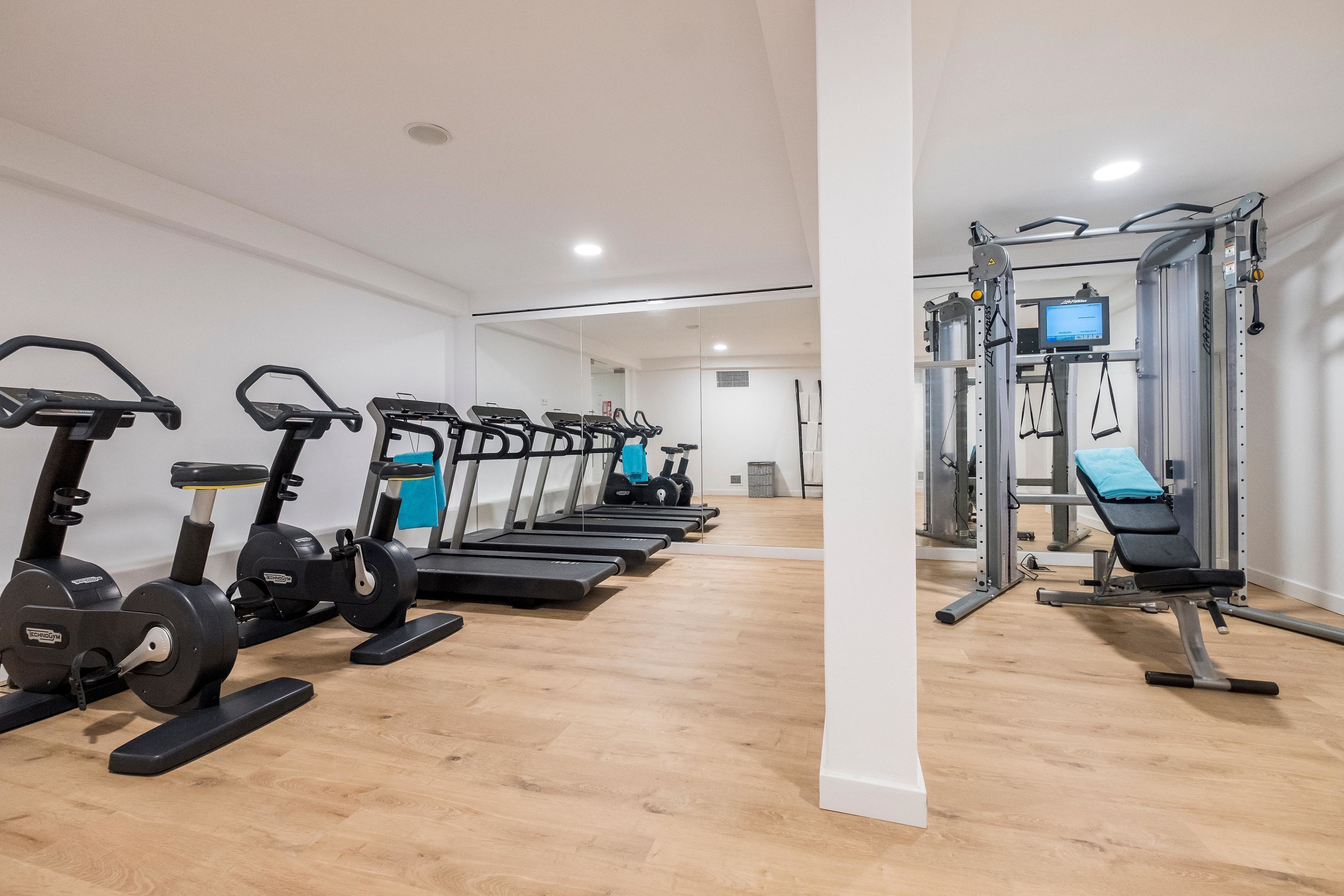 Un gimnasio con cintas de correr, elípticas y equipo de levantamiento de pesas.