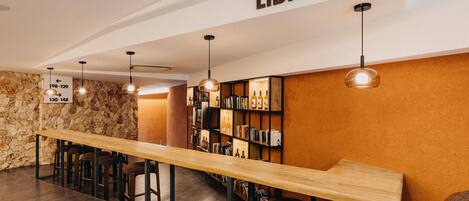 A library with a long wooden table, bookshelves, and hanging pendant lights.