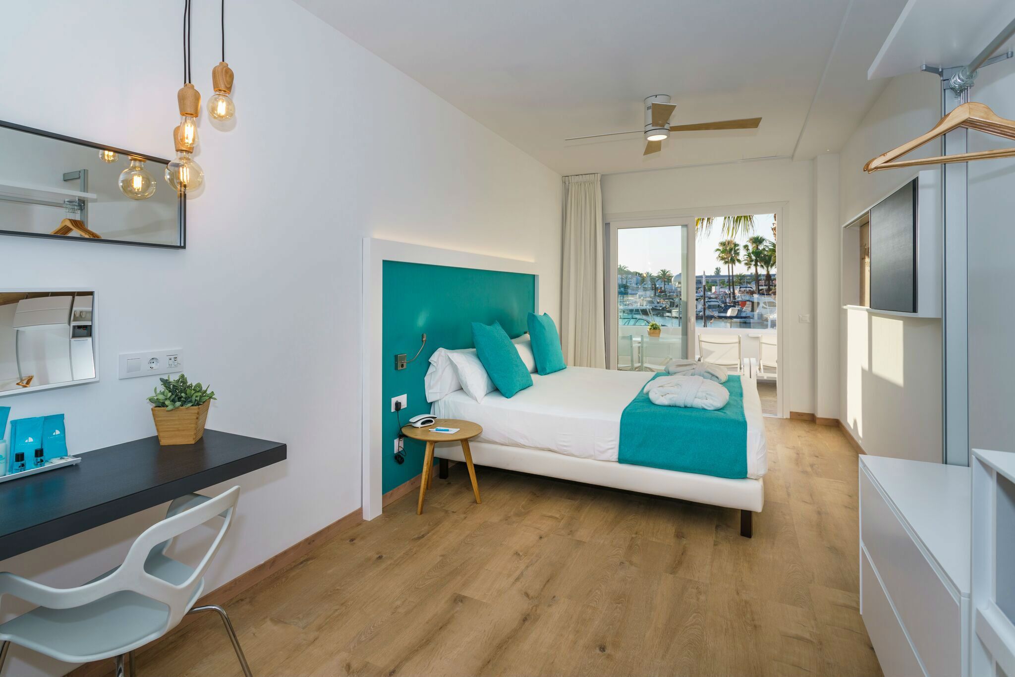 Une chambre d’hôtel moderne équipée d’un lit, d’un bureau, d’une chaise et d’un balcon avec vue.