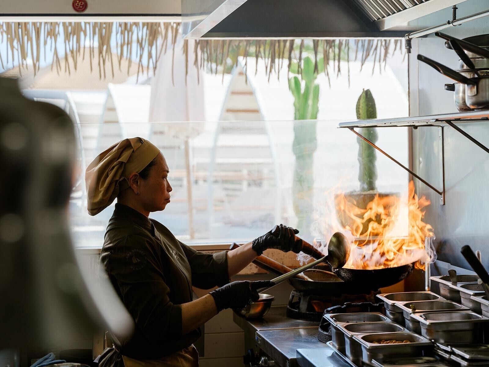 A chef cooking with a large flame visible in a commercial kitchen.