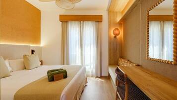 A hotel room with a bed, a desk, a chair, a large mirror, and a ceiling fan.