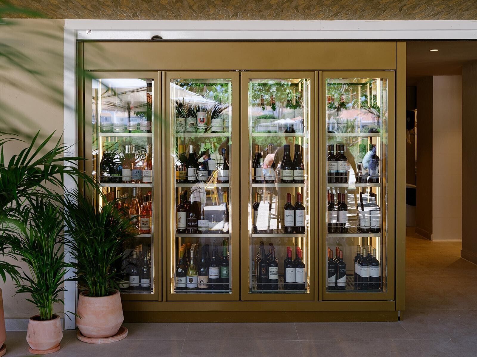 A wine cellar with glass-fronted cabinets containing various bottles.