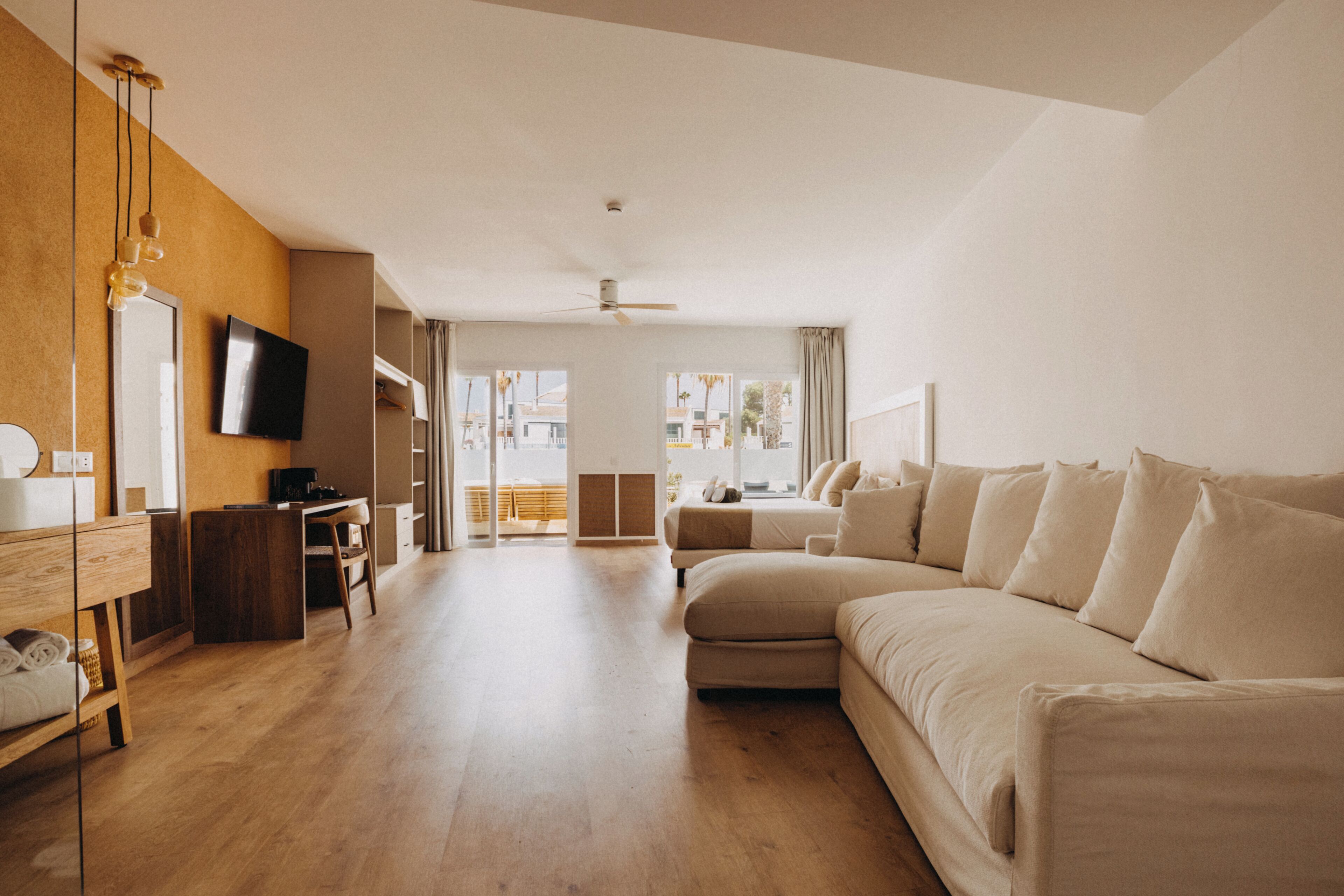 Amplia habitación de hotel con una cama grande, un escritorio, un televisor y vistas al exterior.
