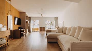 Amplia habitación de hotel con una cama grande, un escritorio, un televisor y vistas al exterior.