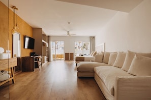 A spacious hotel room with a large bed, a desk, a television, and a view of the outdoors.