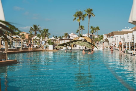 Una piscina al aire libre, sombrillas, sillones reclinables de piscina