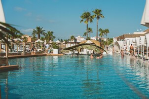 Una piscina al aire libre, sombrillas, sillones reclinables de piscina