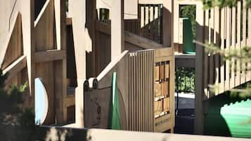 Children can climb and play on this multi-level wooden structure featuring a slide.