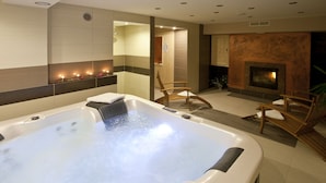 A spa room with a large hot tub, wooden chairs, and a fireplace. - Pensjonat Tatry (Koscielisko)