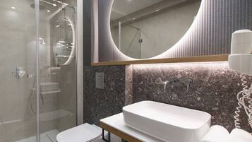 A modern bathroom with a glass-enclosed shower, a white sink, and a large mirror.