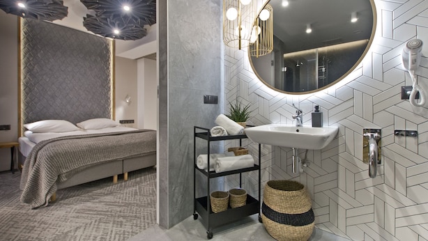 A modern bedroom with a bed, a bedside table, a nightstand, and a wall-mounted mirror. - Pensjonat Tatry (Koscielisko)