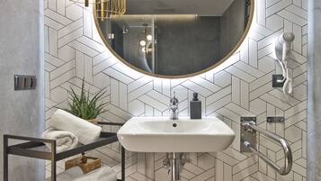 A modern bathroom with a large mirror, a sink, a towel rack, and a shower area.