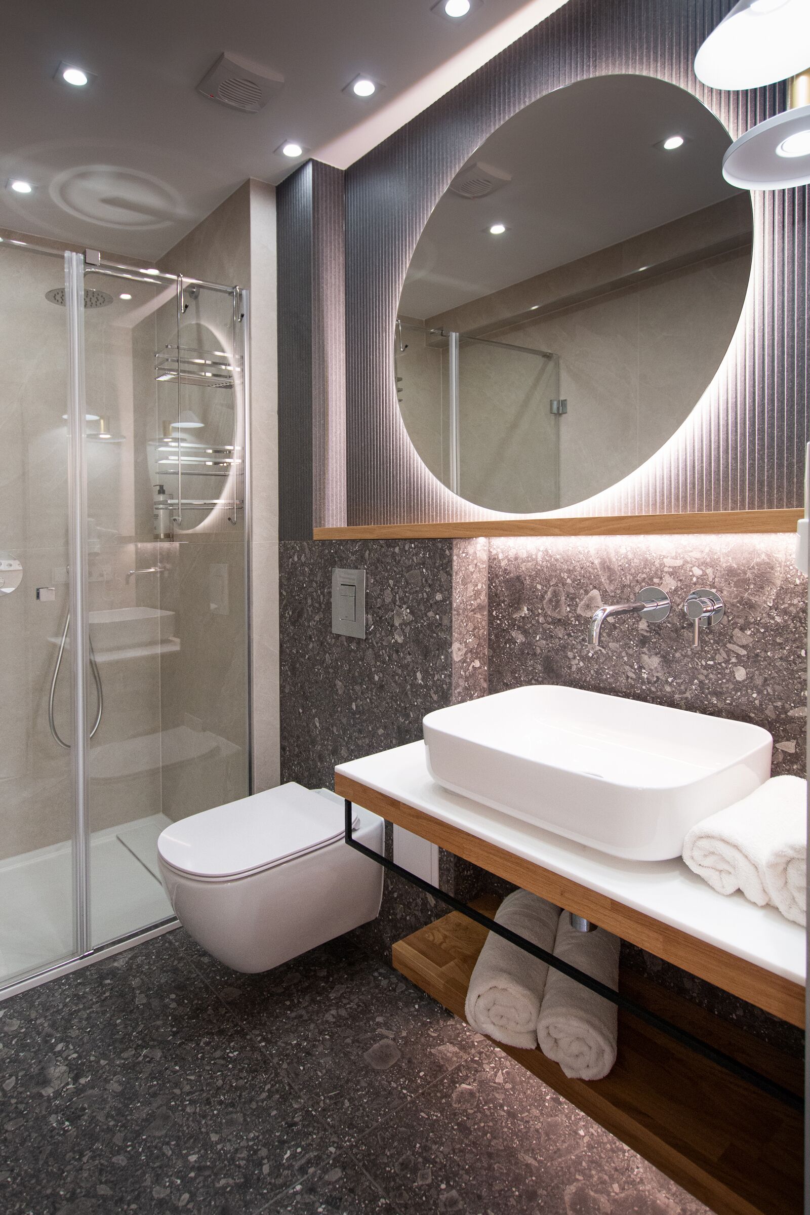 A modern bathroom with a glass-enclosed shower, a white sink, and a large mirror.