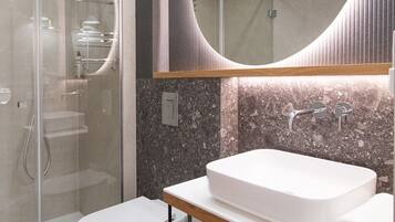 A modern bathroom with a glass-enclosed shower, a white sink, and a large mirror.