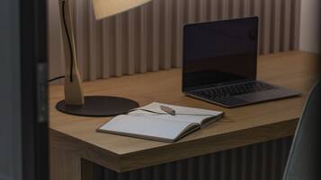 A wooden desk with a laptop, a notebook, and a lamp.