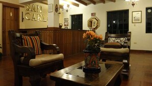 A lobby with wooden furniture, a reception desk, and a chandelier. - Hotel Hospedería San Carlos Villa de Leyva (Villa de Leyva)