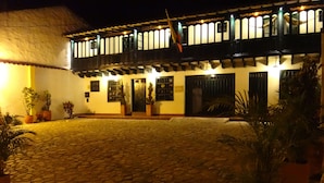 A building with a cobblestone courtyard, wooden balconies, and potted plants. - Hotel Hospedería San Carlos Villa de Leyva (Villa de Leyva)