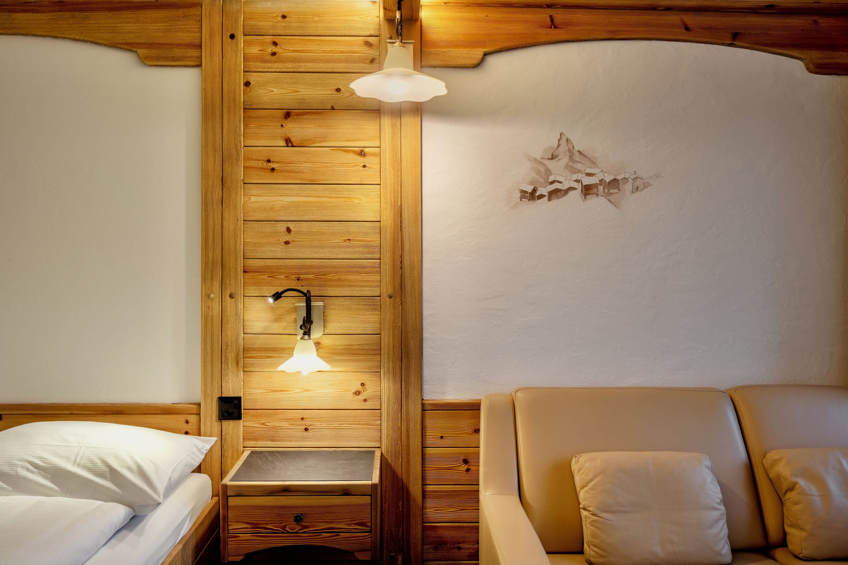 Ein holzgetäfeltes Zimmer im Blockhausstil mit einem Bett, einer kleinen Holzbank und einer Wandleuchte.