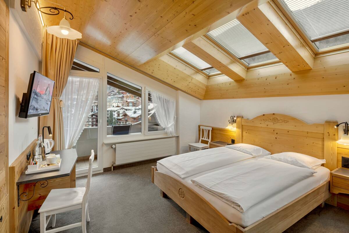 Una habitación de hotel acogedora con dos camas, un escritorio, una silla y un televisor.