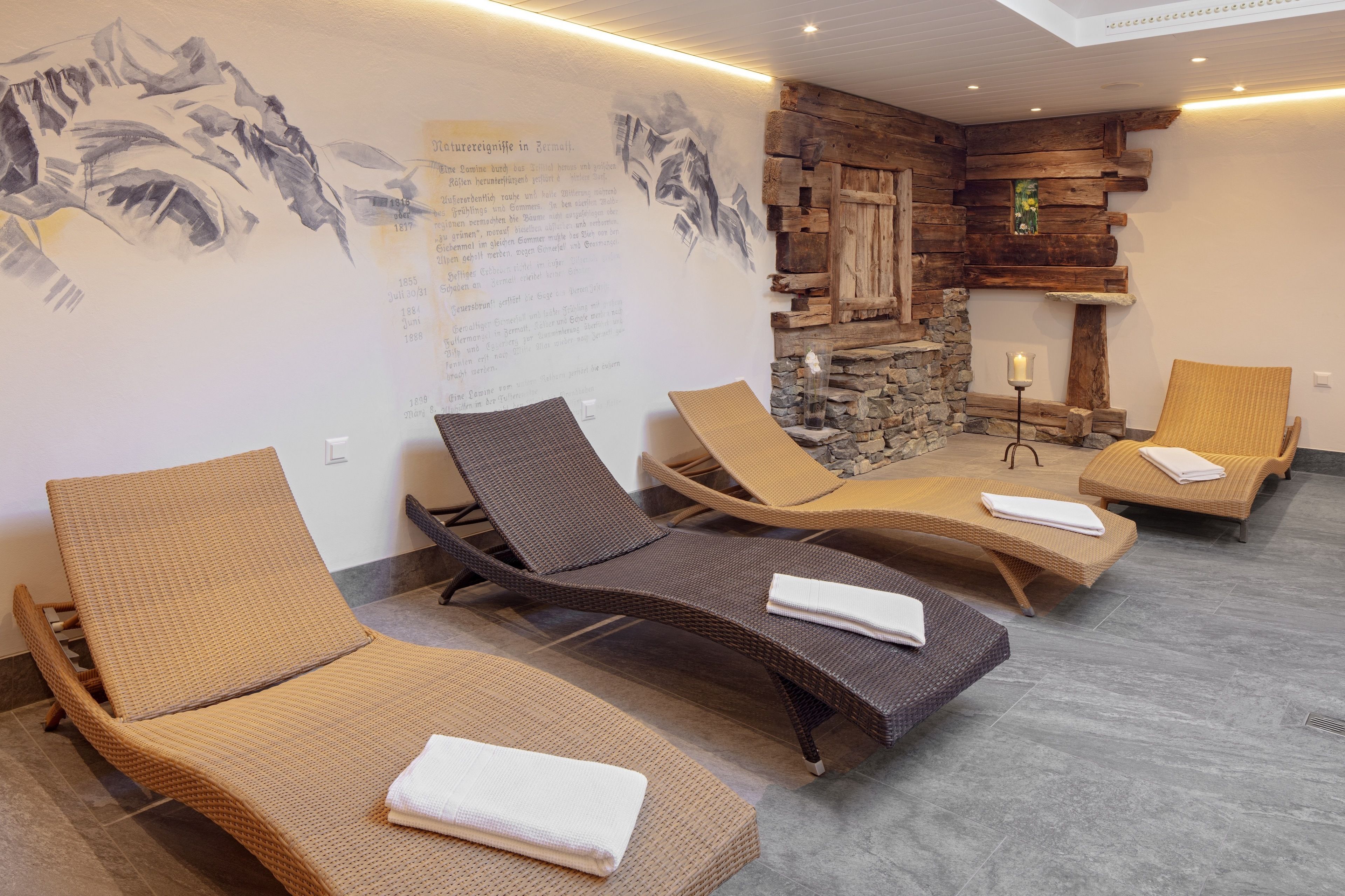 Una stanza spa con quattro poltrone relax, una parete in pietra e un affresco.