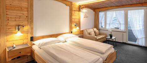 A wooden room with a bed, a chair, and a small table.